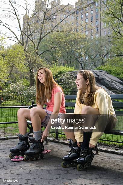 two adolescent girls sitting on a park bench adjusting inline skates, central park, new york city - family sports centre laughing stock pictures, royalty-free photos & images
