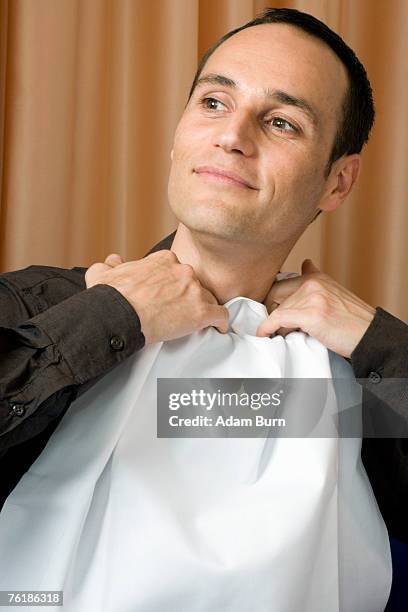 a man tucking a napkin into his shirt collar - kraag stockfoto's en -beelden