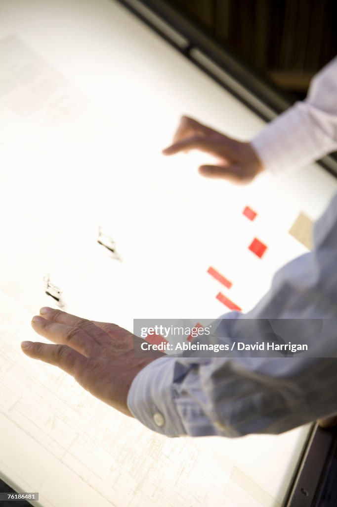 Detail of two businessmen leaning over a light box
