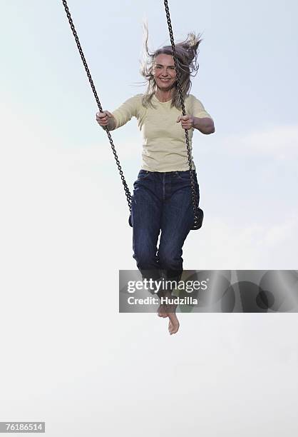 a mature woman on a swing - woman on swing stock pictures, royalty-free photos & images