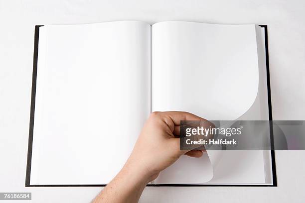 detail of a man turning a page of a blank book - sfogliare libro foto e immagini stock