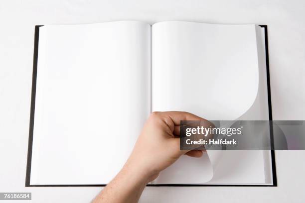 detail of a man turning a page of a blank book - rotate stock pictures, royalty-free photos & images