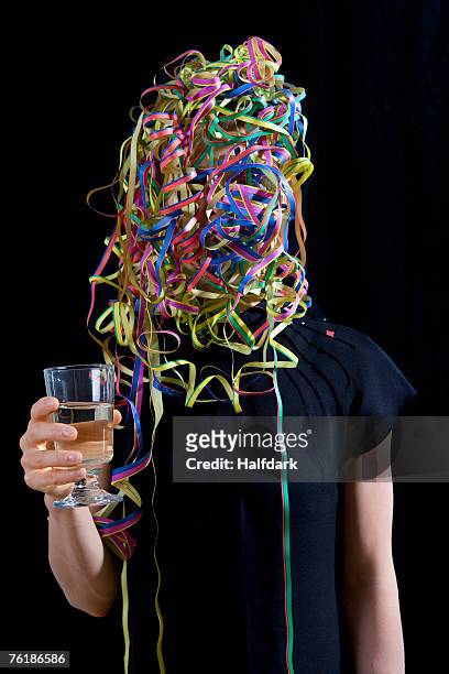 a woman covered in streamers and holding a glass of champagne - woman holding champagne stock-fotos und bilder
