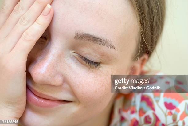 a young woman with her eyes closed and hand over her face - complexion fotografías e imágenes de stock