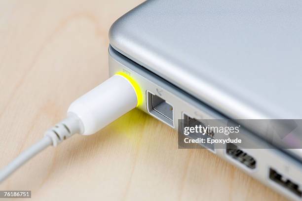 a power cable connected to a closed laptop - tomada de ligação à rede imagens e fotografias de stock