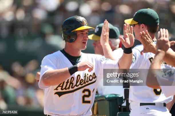 Jack Hannahan of the Oakland Athletics is congratulated by his teammates after scoring a run during the game against the Kansas City Royals at McAfee...