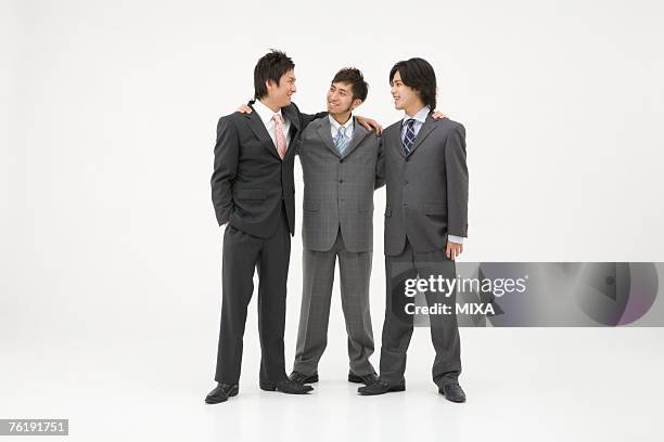 three businessmen standing with arms around each other - three people white background stock pictures, royalty-free photos & images