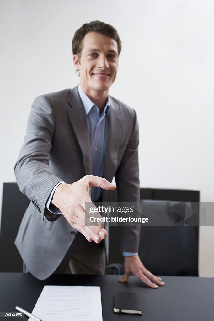 Portrait of young businessman reaching out his hand for welcome
