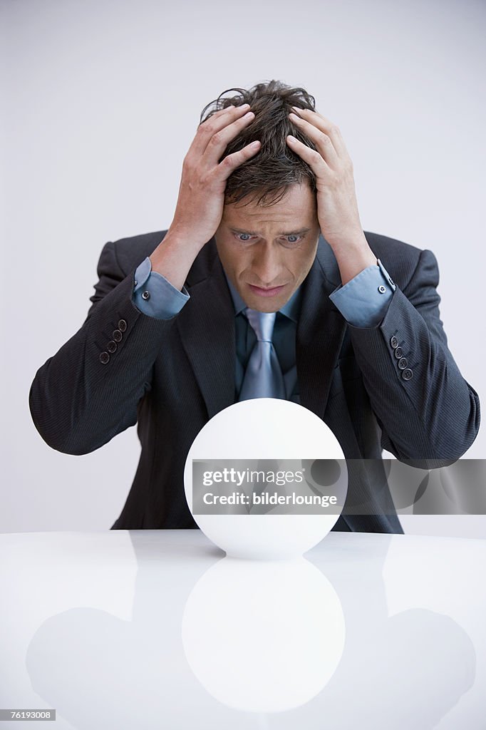 Portrait of businessman shocked by look into crystal ball
