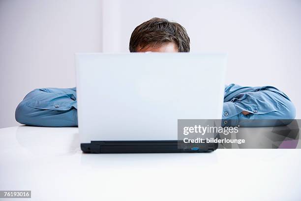 businessman hiding behind laptop computer - hiding behind laptop stock pictures, royalty-free photos & images