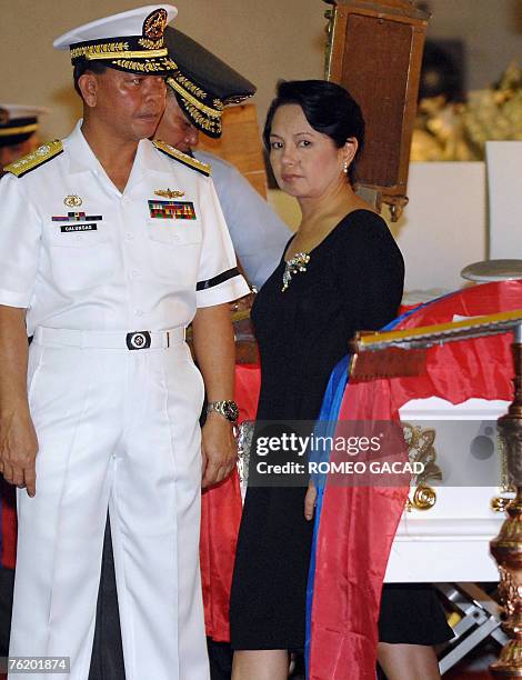 Philippine President Gloria Arroyo accompanied by navy chief Vice Admiral Rogelio Calunsag view the flag-draped caskets of soldiers killed in...