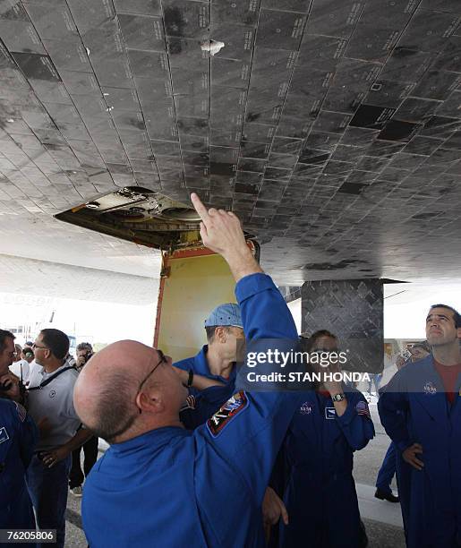 Space shuttle Endeavour Commander Scott J. Kelly points to the damaged tiles on the underbelly of the spacecraft with Canadian Space Agency's Dafydd...