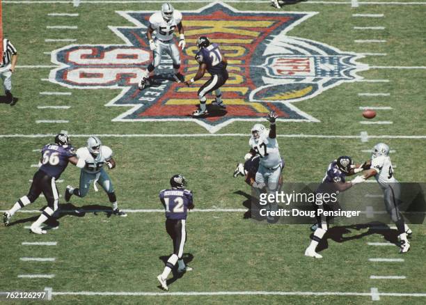 Vinny Testaverde, Quarterback for the Baltimore Ravens throws a pass as Russell Maryland of the Oakland Raiders stretches to intercept the ball...