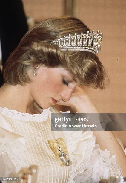 Diana, Princess of Wales, wearing a cream satin dress by Gina Fratini with the Queen Mary Cambridge Lover's Knot Tiara and diamond earrings, looks...