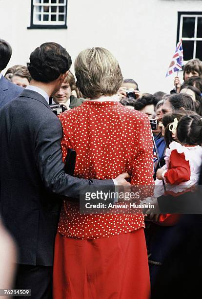 Prince Charles, Prince of Wales puts his arm around his fiance, Lady Diana Spencer, wearing a red and white polka dot suit designed by Jasper Conran,...