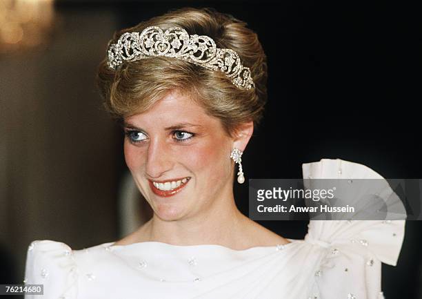 Diana, Princess of Wales, wearing a white dress designed by David and Elizabeth Emanuel with the Spencer Tiara, attends a State Banquet on November...