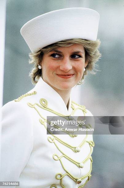 Diana, Princess of Wales, wearing a white military suit with gold majorette drum frogging and epaulettes designed by Catherine Walker and a white hat...