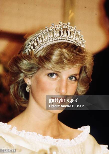 Diana, Princess of Wales, wearing a cream satin dress by Gina Fratini with the Queen Mary Cambridge Lover's Knot Tiara and diamond earrings attends a...