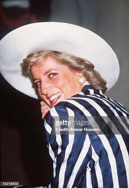 Diana, Princess Of Wales, wearing a silk navy blue and white striped suit designed by Roland Klein and a hat designed by Philip Somerville, smiles as...