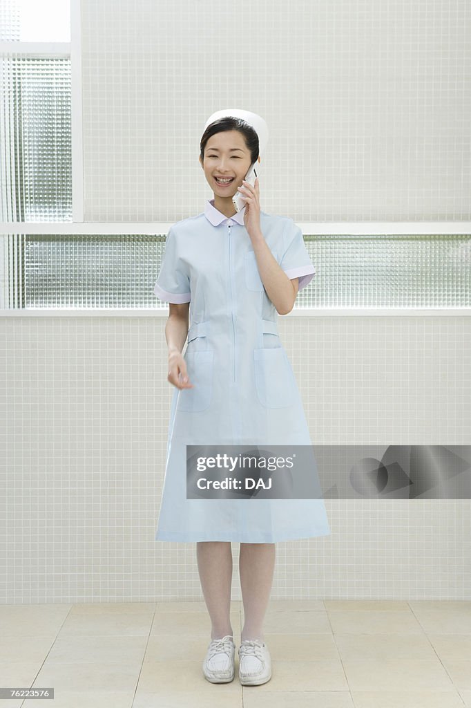 Portrait of a nurse using mobile phone, smiling, front view