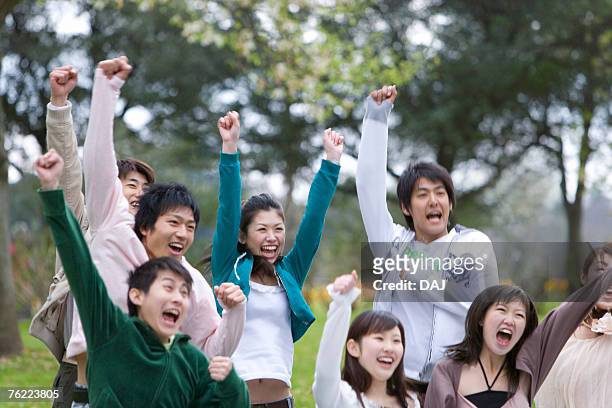 medium group of young people holding fists up in the air, cheering, front view, japan - medium group of people foto e immagini stock