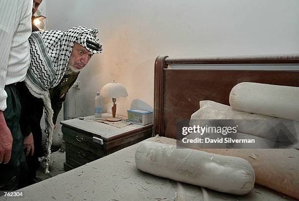 Palestinian leader Yasser Arafat looks at his debris-strewn bed as he inspects the damage to his private quarters on June 6, 2002 in the West Bank...