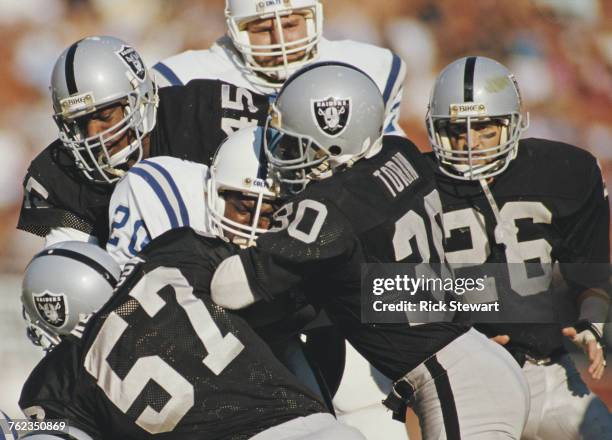 Albert Bentley, Running Back for the Indianapolis Colts is tackled by Stacey Toran, Jerry Robinson and Jerry Robinson for the Los Angeles Raiders...