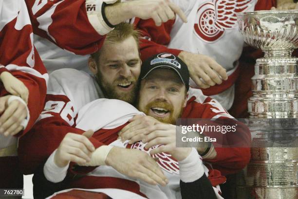 Tomas Holmstrom and Kris Draper of the Detroit Red Wings celebrate with the Stanley Cup after defeating the Carolina Hurricanes in game 5 of the 2002...