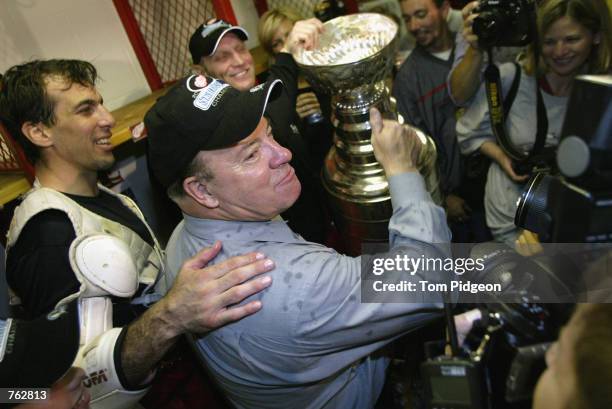 Head coach Scotty Bowman of the Detroit Red Wings is coaxed on by Chris Chelios and Brtett Hull to drink from the Stanley Cup in the lockeroom after...