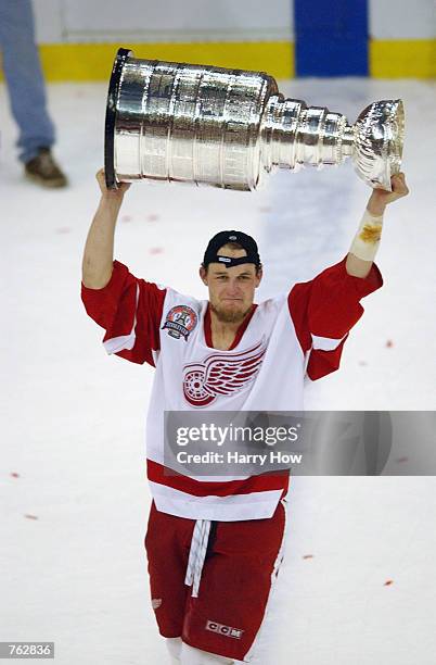 Darren McCarty of the Detroit Red Wings hoists the Stanley Cup after defeating the Carolina Hurricanes 3-1 in game five of the NHL Stanley Cup Finals...