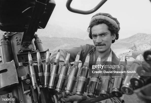 Member of an Afghan Mujahideen group with an anti-aircraft gun and ammunition at a camp at Jegdalay in Kabul Province, Afghanistan, 29th May 1988.