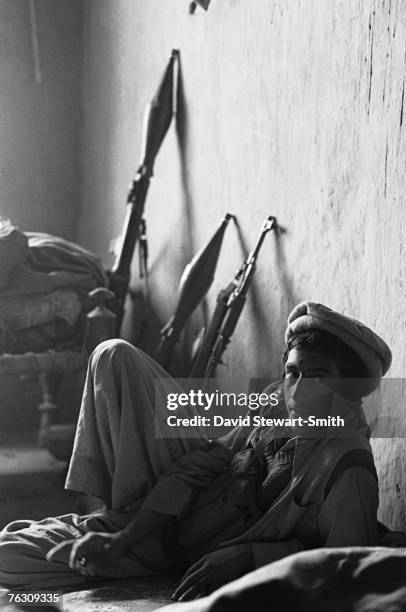 Member of an Afghan Mujahideen group rests during an attack on Jalalabad, Afghanistan, March 1989. Behind him is a Kalashnikov assault rifles and two...