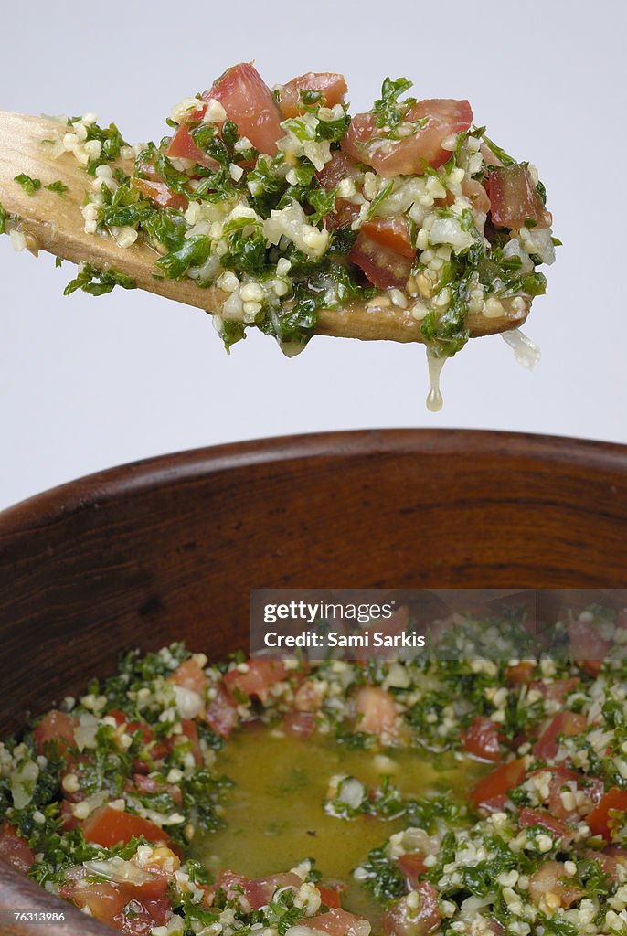 Spoon and bowl containing tabouli, close-up