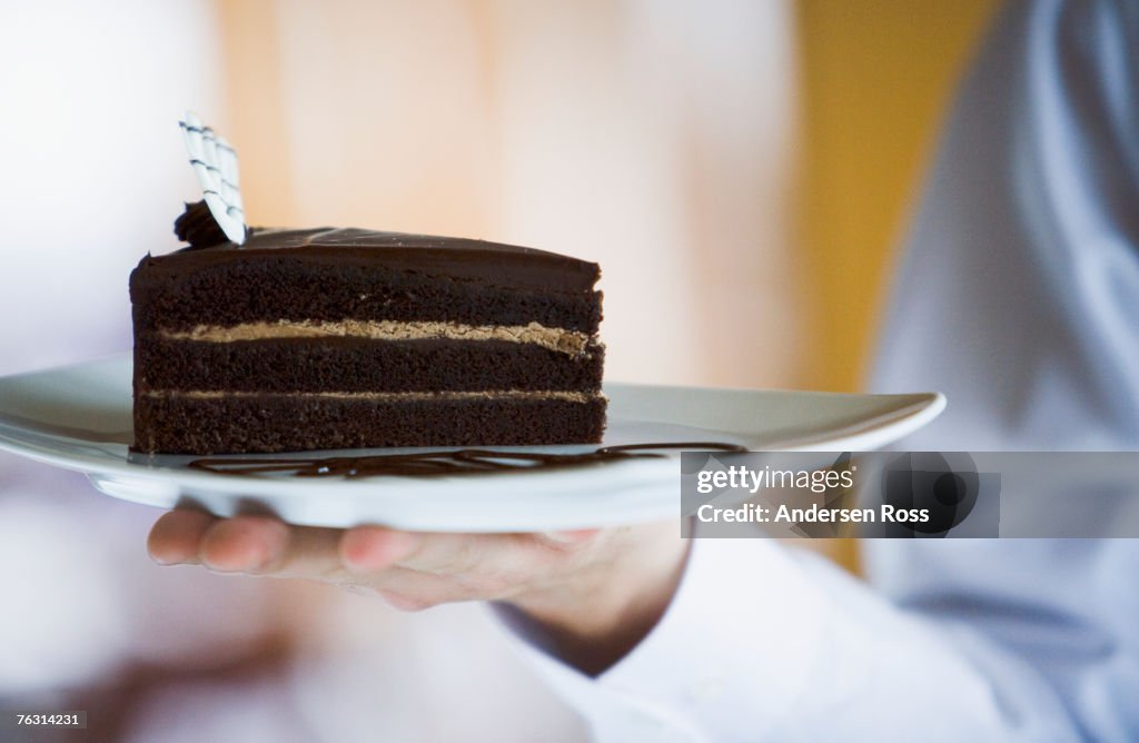 Man holding slice of cake, close-up of hand