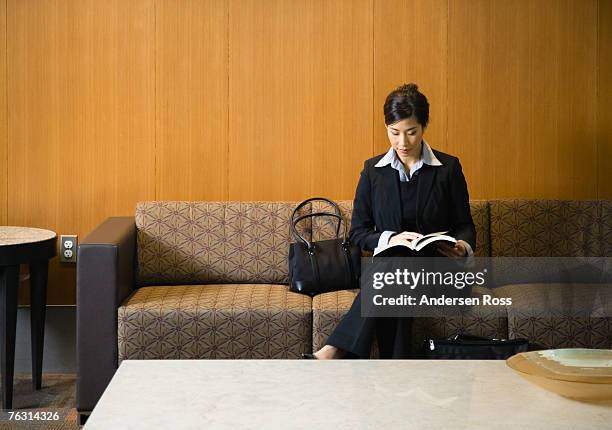business woman reading on couch in reception area - hair back stock pictures, royalty-free photos & images