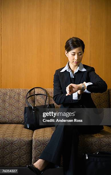 business woman checking watch in reception area - hair back stock pictures, royalty-free photos & images