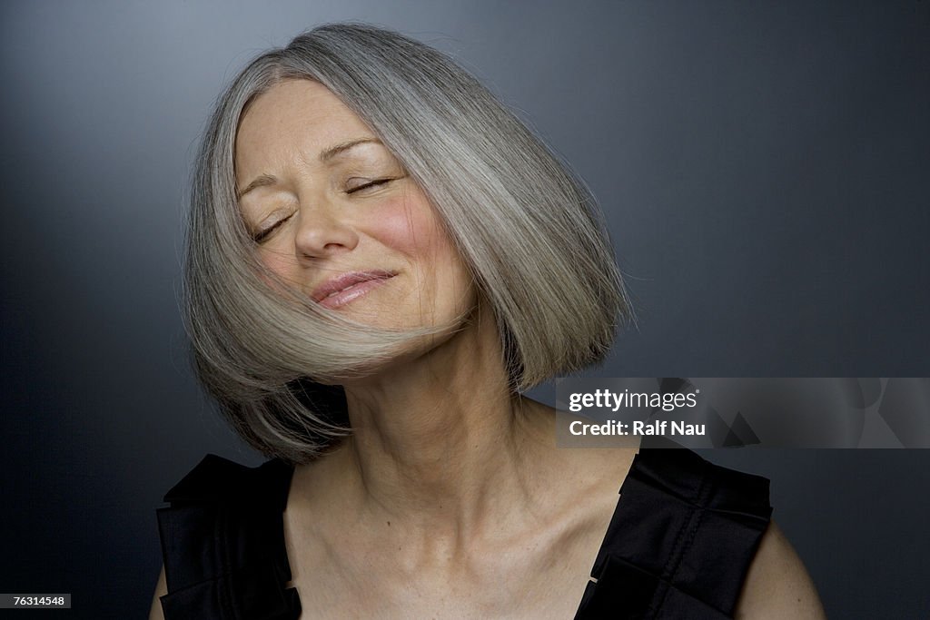 Mature woman turning head, eyes closed, close-up