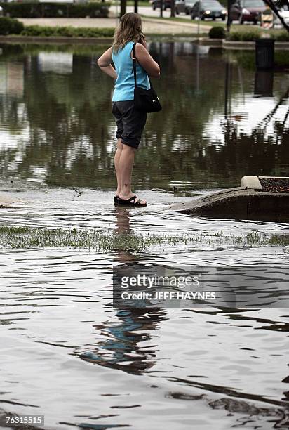 Local resident of Geneva, Illinois talks on her cell phone 24 August, 2007 from a flooded parking area along the Fox River in Illinois. Flooding...