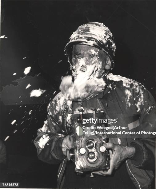 Polish-born American photographer Weegee , camera in hand, closes his eyes as a cream pie flies at him during filming on the set of the Stanley...