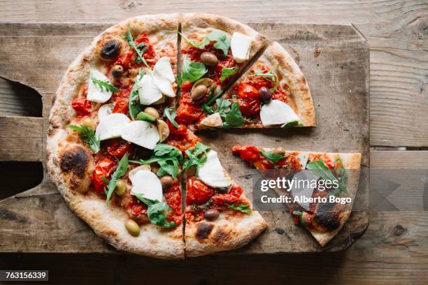 sliced pizza on chopping board, overhead view - fresh mozzarella pizza photos et images de collection