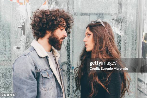 young man and woman, standing face to face, pensive expressions - fighting imagens e fotografias de stock