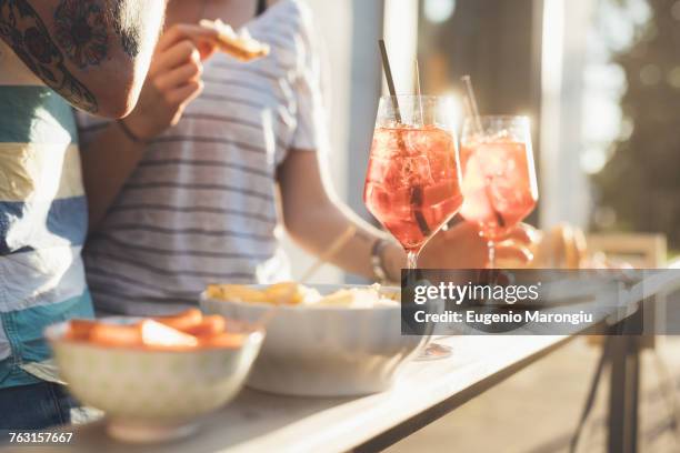 cropped shot of couple eating tapas at sunlit sidewalk cafe - milan cafe stock pictures, royalty-free photos & images