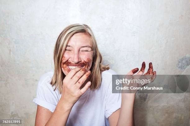 portrait of woman with chocolate on hands and around mouth, laughing - avoir faim photos et images de collection