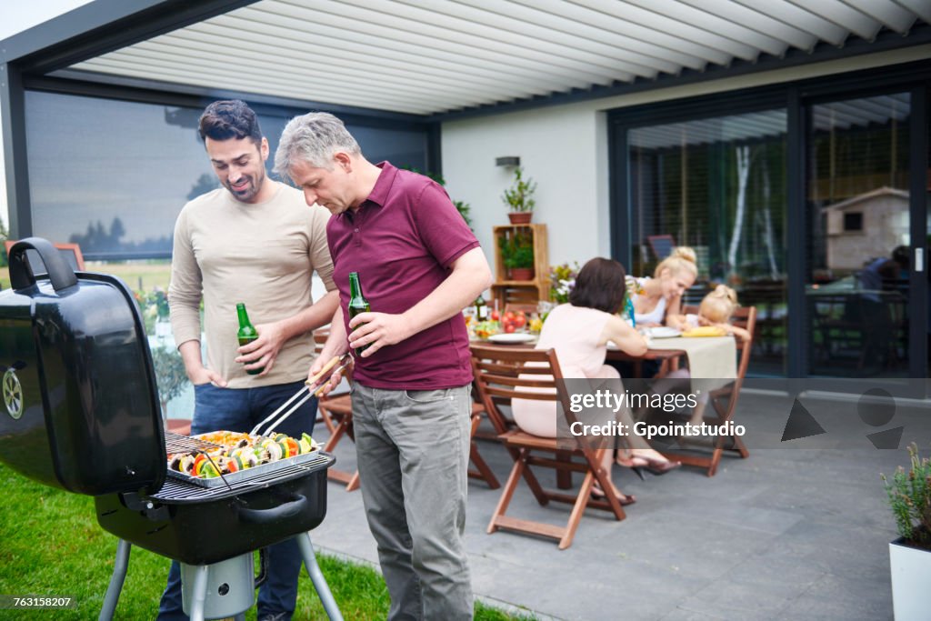 Mature and mid adult man barbecuing at family lunch on patio