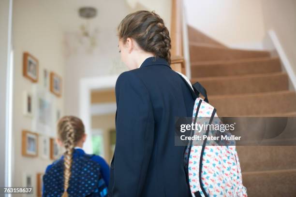 rear view of teenage schoolgirl and sister in uniforms in hallway - schoolgirl stock pictures, royalty-free photos & images