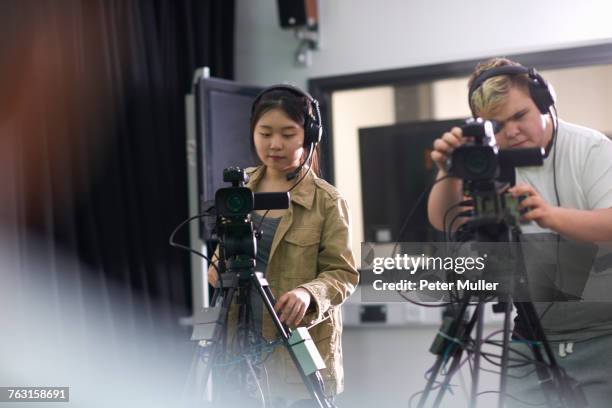 over shoulder view of college students filming in tv studio - filmteam stockfoto's en -beelden