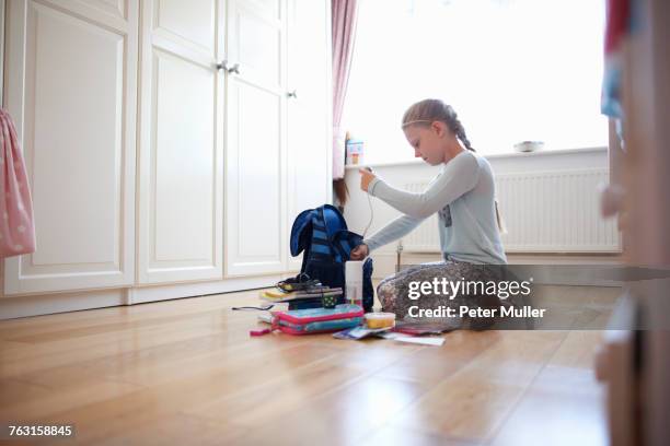 girl kneeling on floor packing school bag - skolväska bildbanksfoton och bilder