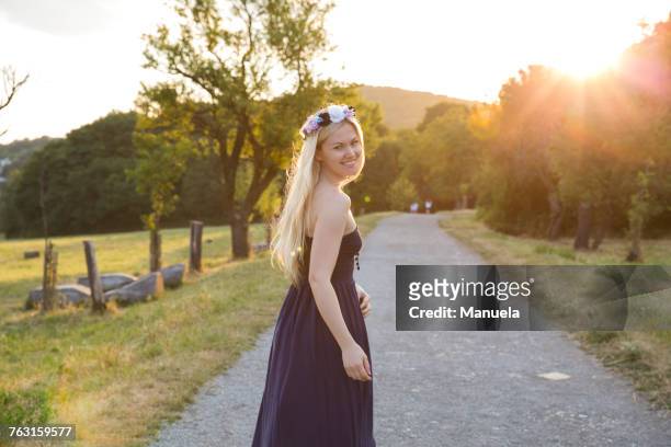 woman on rural road wearing strapless dress looking over shoulder at camera smiling - strapless stock-fotos und bilder