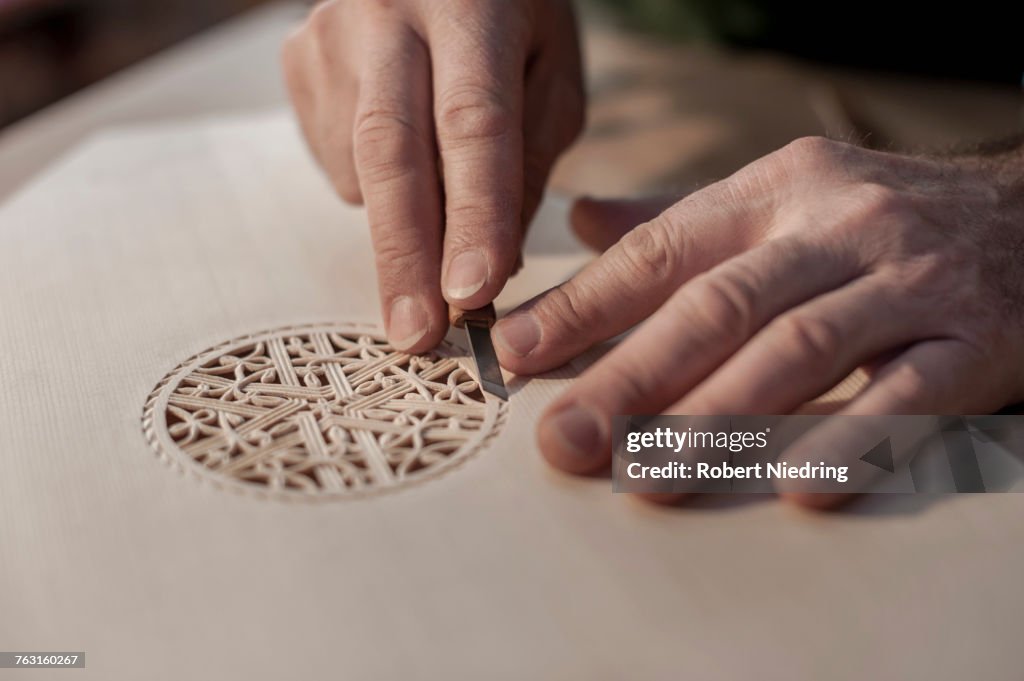 Lute manufacturer carving out ornament out of wood