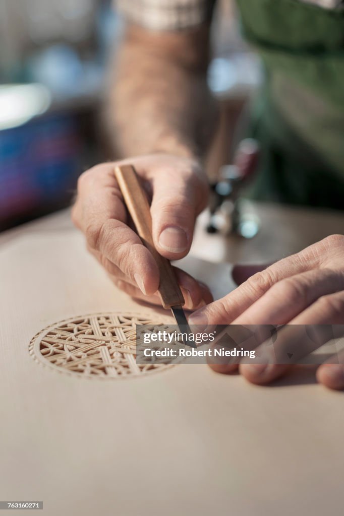 Lute manufacturer carving out ornament out of wood